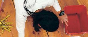 Eine Frau kniet auf einem Dielenboden und putzt