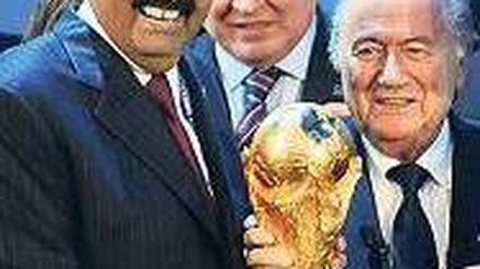 Hand am Cup. Scheich Hamad bin Khalifa Al-Thani (l.) durfte sich 2010 über den WM-Zuschlag für Katar freuen. Foto: AFP