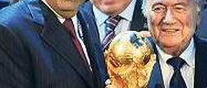 Hand am Cup. Scheich Hamad bin Khalifa Al-Thani (l.) durfte sich 2010 über den WM-Zuschlag für Katar freuen. Foto: AFP