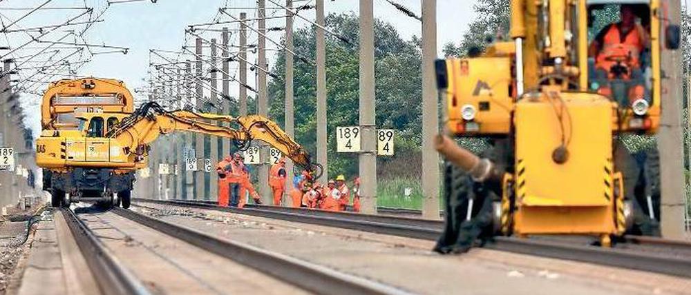 Bagger und Arbeiter in orangefarbenen Schutzanzügen stehen auf den Schienen der gesperrten Bahntrasse