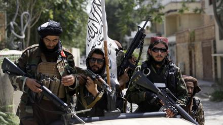 Schwer bewaffnete Taliban-Kämpfer patrouillieren nach ihrer Machtübernahme mit wehender Flagge des Islamischen Emirats Afghanistan durch Kabul.