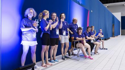 Volunteers helfen bei den Schwimmwettbewerben der Special Olympics. 