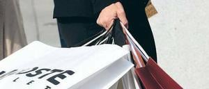 Eine Frauenhand hält zahlreiche Einkaufstüten.