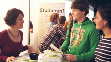 Junge Studierende stehen an einem Infostand.
