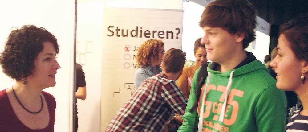 Junge Studierende stehen an einem Infostand.