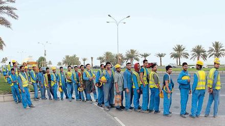 Arbeitsmigranten warten nahe der Corniche im Herzen Dohas auf ihren Bustransfer zur Baustelle.