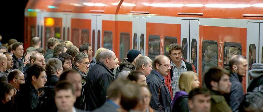 Reisende drängeln sich an einem Nahverkehrszug der Bahn. 