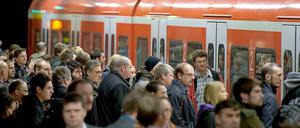 Reisende drängeln sich an einem Nahverkehrszug der Bahn. 