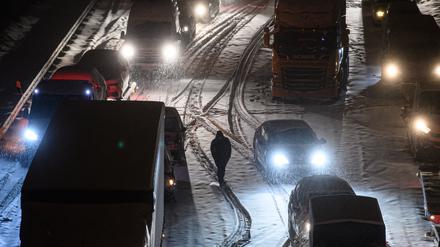 Autos und Lastwagen stehen am frühen Morgen bei Schneefall auf der verschneiten Autobahn 4 bei Dresden im Stau (Archivbild vom 08.02.2021).