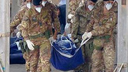 Tod vor Lampedusa. Italienische Soldaten tragen die Leiche eines Opfers. Foto: AFP
