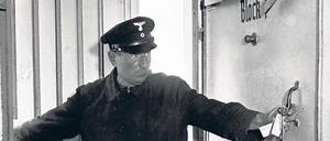 Ein Mann in Uniform öffnet die Tür eines Luftschutzbunkers.