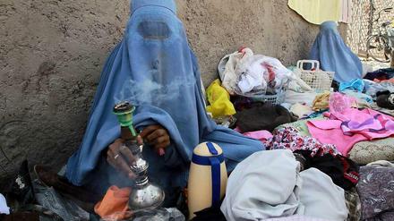 Auch nach zwölf Jahren Nato-Einsatz ist in Afghanistan vieles beim Alten: Eine Frau in Burka verkauft am Straßenrand in Herat alte Kleider.