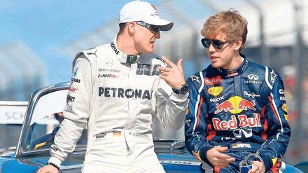 Rot ist deine Farbe! Michael Schumacher (l.) will Sebastian Vettel zu Ferrari lotsen. Foto: dpa