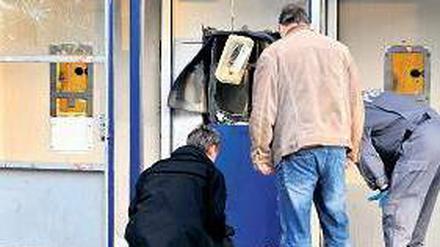 Gesprengt. Ermittler begutachten den beschädigten Geldautomaten. Foto: dpa