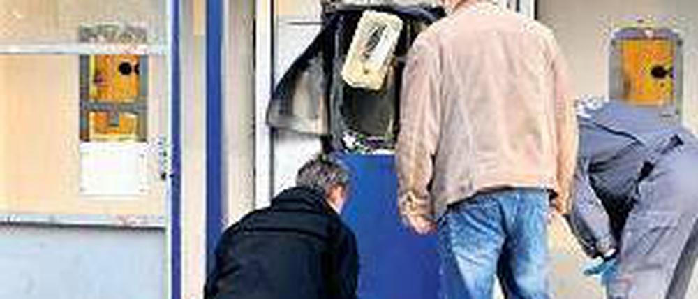 Gesprengt. Ermittler begutachten den beschädigten Geldautomaten. Foto: dpa