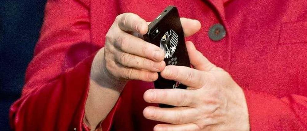 Auf der Computermesse CeBit begutachtet Merkel ein Handy mit Bundesadler. Dass ihr eigenes abgehört werden könnte, hatte sie sicher nicht vermutet.