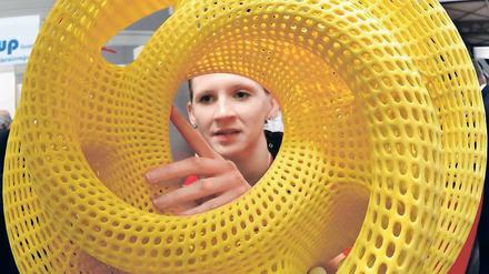 Eine Frau begutachtet ein rundes, gelbes Plastikgebilde.