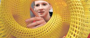 Eine Frau begutachtet ein rundes, gelbes Plastikgebilde.