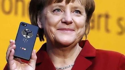 Bundeskanzlerin Angela Merkel hält ein Smartphone in der Hand.