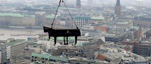 Ein Flügel hängt an einer Vorrichtung über den Dächern von Hamburg.