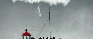 Monsterwelle. Etwa 30 Meter hoch ist diese Welle vor Nazaré in Portugal, auf der ein winziger Surfer zu sehen ist. 