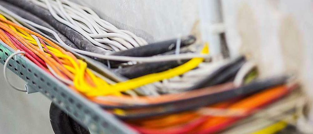 Bunte Kabel führen in eine Wand