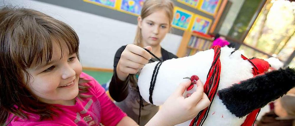 Zwei Schülerinnen bei Handarbeiten an einem Steckenpferd.