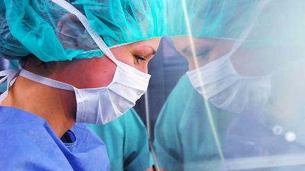 Im Unfallkrankenhaus Berlin blickt eine Krankenschwester mit Mudschutz durch eine Scheibe in den Operationssaal.