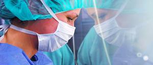 Im Unfallkrankenhaus Berlin blickt eine Krankenschwester mit Mudschutz durch eine Scheibe in den Operationssaal.
