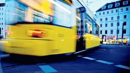 Eine gelbe Berliner Straßenbahn fährt über den Rosenthaler Platz. 