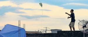 Junge lässt in einer Favela einen Drachen steigen.