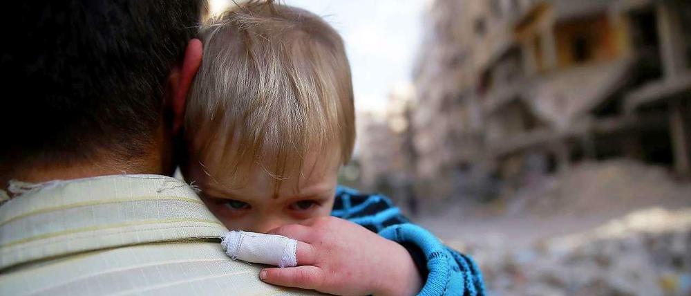 Ein verletztes syrisches Kind auf dem Arm eines Mannes in Damaskus