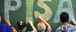 Vier Schüler malen zusammen den Schriftzug Pisa an eine Tafel.