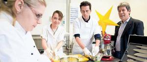 Kochkünstler. Mandy Ressel, 25, (l.) und Maika Bumenthal, 19, wissen, wie man richtig gute Pizzataschen zubereitet. Lehrer Emanuele Manciavillano gibt in der Lehrküche Tipps. Auch der zuständige ajb-Leiter Reinhold Kolkmann-Weisel dankt den Tagesspiegel-Lesern, die große Teile der Gastro-Einrichtung durch Spenden ermöglichten.