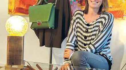 Die Inhaberin vor einer Schaufensterpuppe, der eine grüne Tasche umhängt