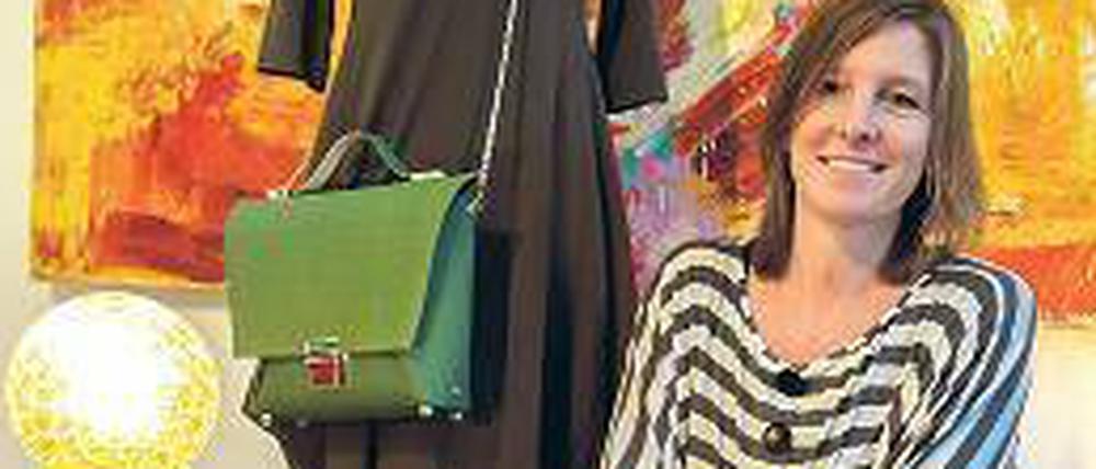 Die Inhaberin vor einer Schaufensterpuppe, der eine grüne Tasche umhängt