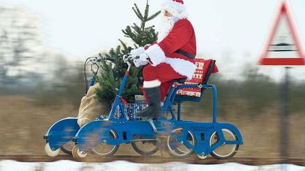 Ungewöhnliche Wege: Weihnachtsmänner müssen erfinderisch sein, um alle Geschenke pünktlich auszuliefern. In Brandenburg bringen sie die Präsente notfalls mit der Draisine. Paketdienste machen weniger Aufhebens. Sie liefern per Auto. Foto: dpa/pa