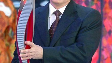 Feuer und Eis: Russlands Präsident Wladimir Putin trägt die Olympische Fackel