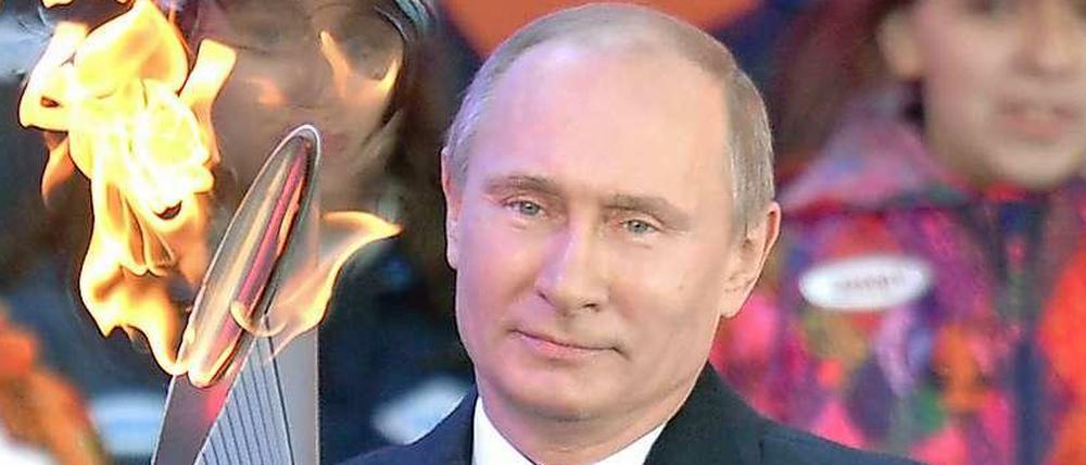 Feuer und Eis: Russlands Präsident Wladimir Putin trägt die Olympische Fackel