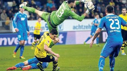 In der Schwebe. Das Publikum in Sinsheim sah ein rasantes Spiel mit vielen Möglichkeiten auf beiden Seiten, hier macht der ansonsten eher unsicher agierende Hoffenheimer Torwart Jens Grahl eine Chance der Dortmunder zunichte. Foto: AFP