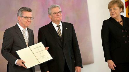 Bundespräsident Joachim Gauck überreicht am Dienstag im Schloss Bellevue in Berlin die Ernennungsurkunde an den neuen Bundesinnenminister, Thomas de Maizière (l, CDU). Rechts steht Kanzlerin Angela Merkel (CDU).