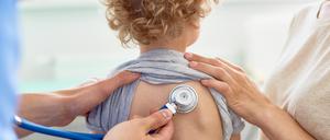 Unrecognizable male pediatrician examining curly little patient with help of stethoscope, blurred background