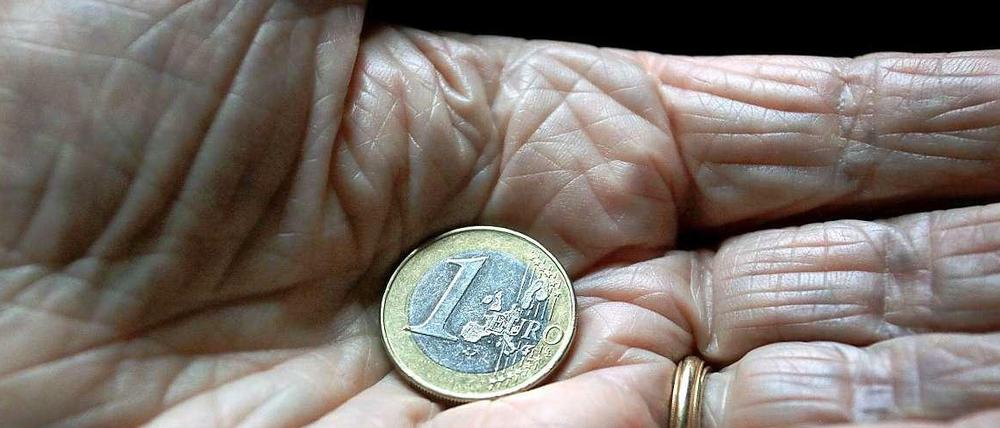 In der Hand eines alten Menschen liegt eine Euro-Münze