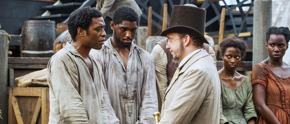 Gefangen. Salomon Northup (Chiwetel Ejiogfor, lks.) ist gekidnapt worden. Anderntags steht vor dem Sklavenhalter (Paul Giamatti).