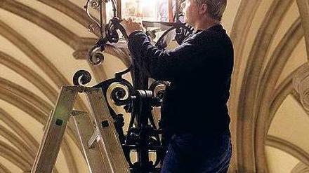 Auftritt. Während Hamburgs Bürgermeister am Donnerstag den Stromnetz-Deal vorstellte, tauschte ein Haustechniker in der Empfangshalle des Rathaus eine Lampe aus. Foto: dpa