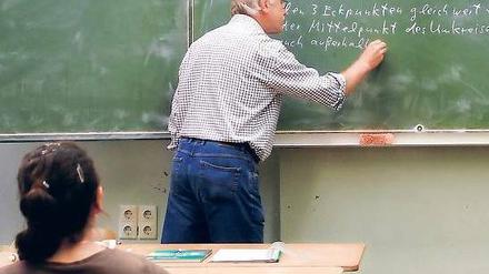Ein Lehrer schreibt eine mathematische Formel an die Tafel.