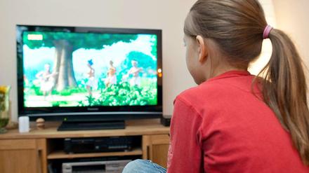 Ein Mädchen sitzt vor dem Fernseher.