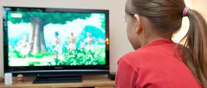 Ein Mädchen sitzt vor dem Fernseher.