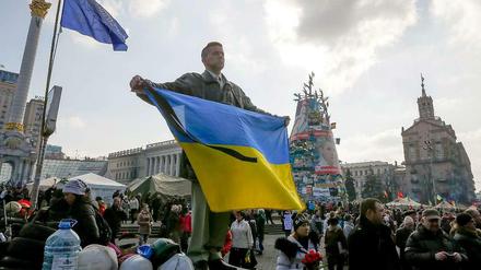 Ein Ukrainer hält während einer Trauerzeremonie die ukrainische Flagge hoch.