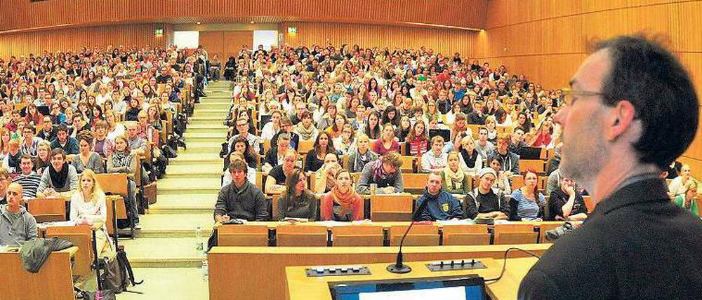 Ein Professor spricht in einem Hörsaal zu Studierenden.